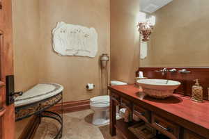 Half bathroom featuring toilet, tile patterned floors, and vanity