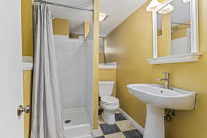 Bathroom featuring toilet, a stall shower, a textured ceiling, and baseboards