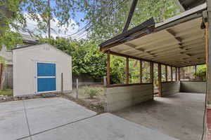 View of patio featuring a storage unit, an outbuilding, and fence