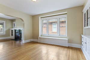 Living room with light wood-style floors, arched walkways, plenty of natural light, and baseboards