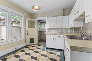 Kitchen with a sink, light countertops, plenty of natural light, and white cabinetry