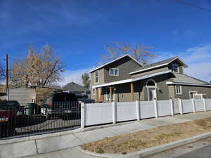 View of front of property featuring a fenced front yard, stucco siding, covered porch, and roof with shingles