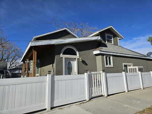 View of front of house featuring stucco siding, a gate, and a shingled roof