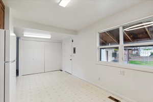 Interior space with freestanding refrigerator, light floors, and baseboards