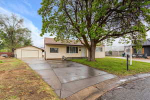 View of front of house featuring a garage, a front yard, an outbuilding, and driveway