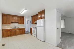Kitchen featuring white appliances, light countertops, brown cabinets, and decorative backsplash