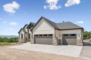 Craftsman-style home with driveway, an attached garage, stone siding, and roof with shingles
