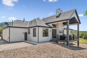Rear view of house with roof with shingles, a patio area, and a chimney