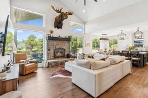 Living area featuring recessed lighting, wood-type flooring, a stone fireplace, ceiling fan, and high vaulted ceiling