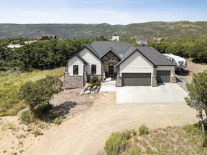 View of front of property featuring concrete driveway, an attached garage, stone siding, and a mountain view