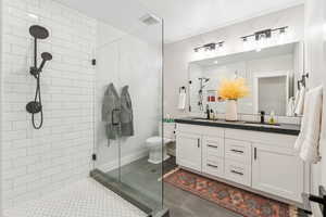 Bathroom featuring a stall shower, double vanity, and tile patterned flooring