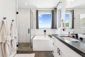 Full bath featuring vanity, a shower stall, a garden tub, recessed lighting, and tile walls