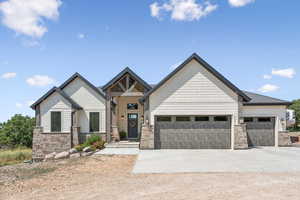 View of front of property featuring stone siding, driveway, and a garage