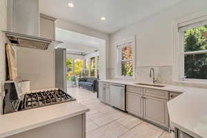 Kitchen featuring stainless steel dishwasher, a sink, light countertops, tasteful backsplash, and recessed lighting