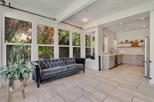 Sunroom with beamed ceiling, a sink, and recessed lighting