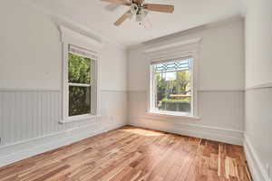 Spare room with hardwood / wood-style floors, wainscoting, crown molding, and ceiling fan