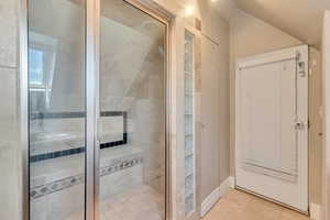 Bathroom featuring a shower stall, tile patterned floors, and vaulted ceiling