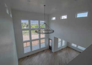 Unfurnished living room featuring baseboards, a chandelier, and wood finished floors