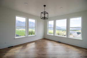 Unfurnished dining area featuring a chandelier, baseboards, a mountain view, and wood finished floors