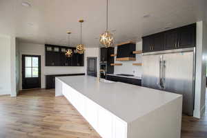 Kitchen featuring appliances with stainless steel finishes, a sink, light wood-style flooring, a textured ceiling, and open shelves