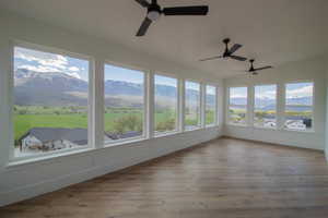 Unfurnished sunroom with plenty of natural light, a mountain view, wood finished floors, and lofted ceiling