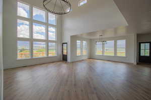 Unfurnished living room with a chandelier, baseboards, and wood finished floors