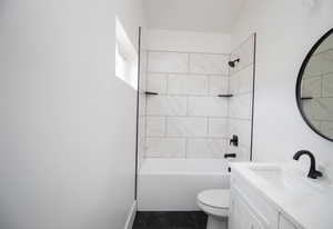 Full bathroom with vanity, toilet, marble look tiles, and  shower combination