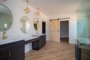 Bathroom featuring wood finished floors, double vanity, and baseboards