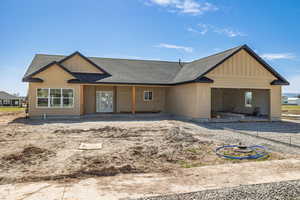 View of front of house with board and batten siding, an attached garage, and a shingled roof