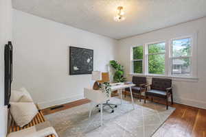 Office with baseboards, hardwood / wood-style floors, and a textured ceiling