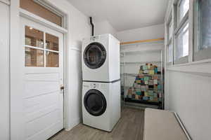 Laundry area featuring estacked washer and dryer, wood finished floors, and healthy amount of natural light
