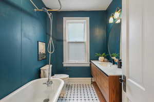 Full bathroom with a soaking tub, toilet, vanity, baseboards, and tile patterned floors