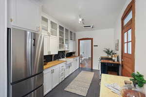 Kitchen featuring appliances with stainless steel finishes, a sink, white cabinets, and glass insert cabinets