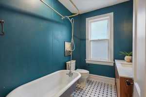 Full bath with a freestanding tub, toilet, vanity, and baseboards