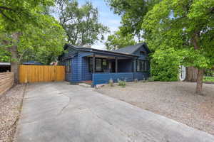 Bungalow-style home featuring concrete driveway, fence, a gate, a chimney, and covered porch