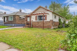 Bungalow-style home with a chimney, brick siding, and a front lawn