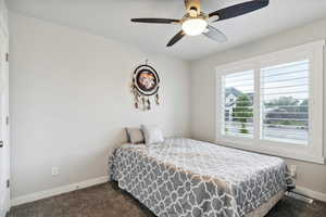 Bedroom with dark carpet, baseboards, and a ceiling fan