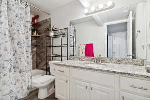 Bathroom featuring toilet, shower / bath combination with curtain, vanity, and wood finished floors