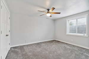 Carpeted empty room featuring a ceiling fan, baseboards, and a textured ceiling