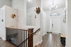 Foyer with a chandelier, wood finished floors, and baseboards