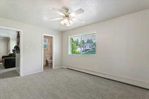 Unfurnished bedroom featuring a baseboard radiator, a textured ceiling, carpet floors, baseboards, and a ceiling fan