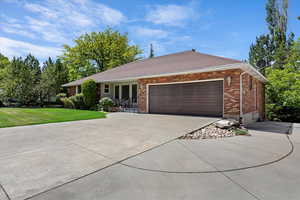 Ranch-style home featuring concrete driveway, brick siding, a front lawn, and an attached garage