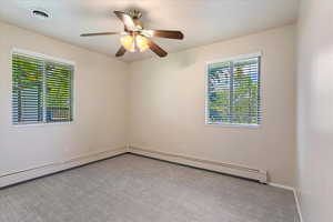 Carpeted spare room with a ceiling fan and baseboards