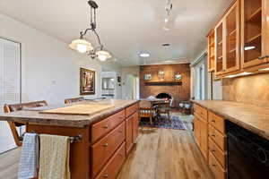 Kitchen with track lighting, dishwasher, light wood finished floors, a center island, and a fireplace