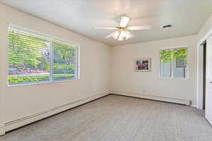 Carpeted empty room with a textured ceiling, a baseboard radiator, a ceiling fan, and baseboards