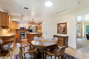 Dining space with rail lighting, light wood-type flooring, and baseboards
