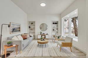 Living area with built in features, wood finished floors, and baseboards