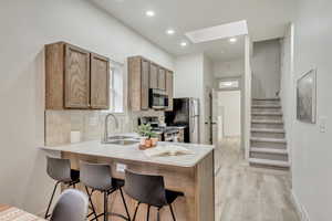 Kitchen with stainless steel appliances, a sink, a kitchen breakfast bar, a skylight, and recessed lighting