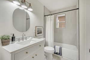Full bath with toilet, shower / bath combo with shower curtain, and vanity