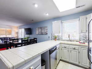 Kitchen featuring dishwasher, open floor plan, a sink, a peninsula, and tasteful backsplash